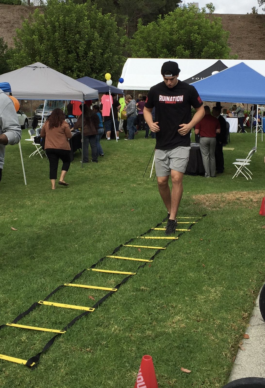 Employee running an agility ladder drill at an outdoor fair