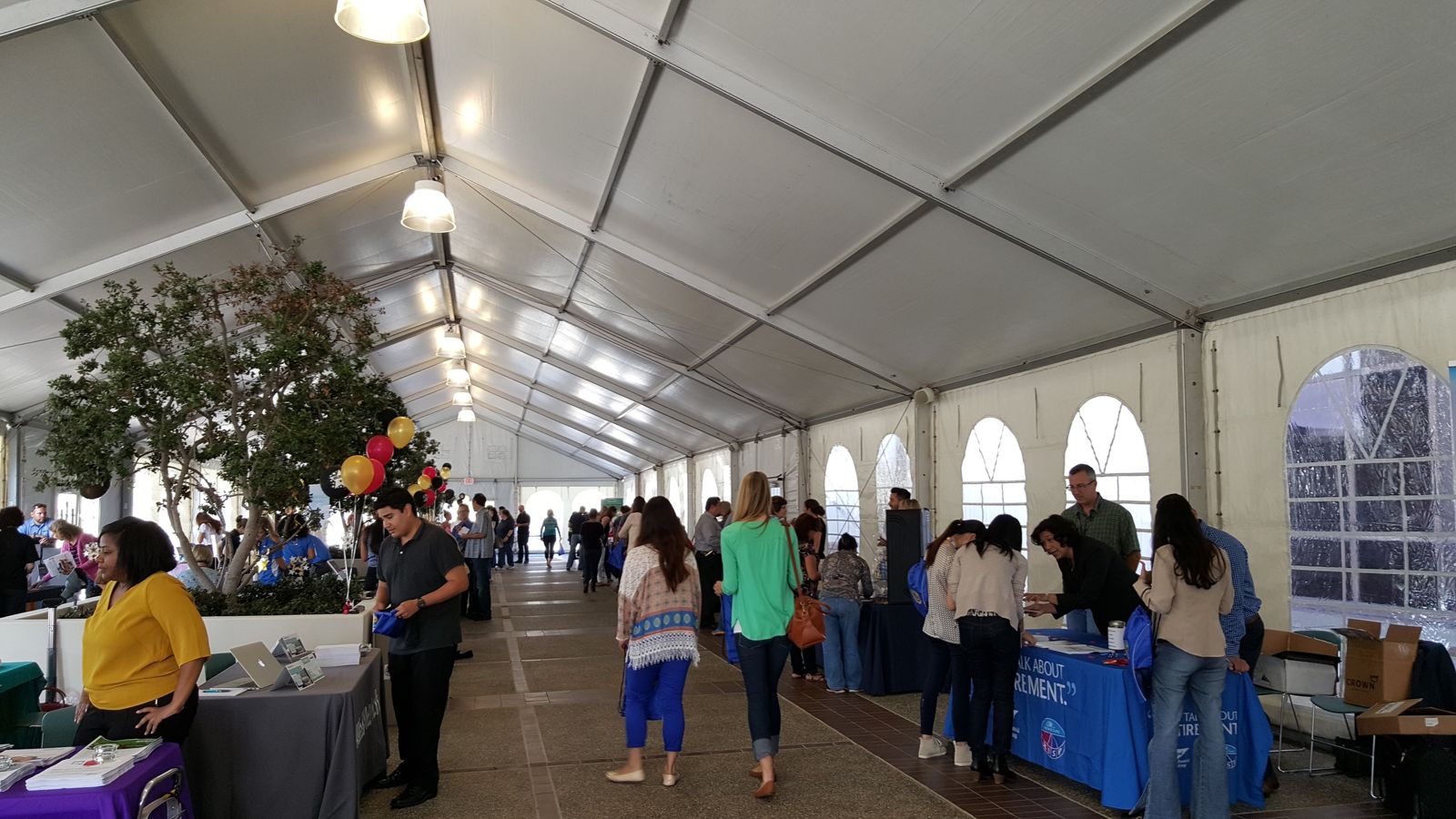 Employees visiting wellness vendor tables inside a large event tent